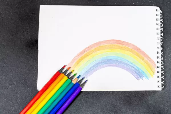 Notebook with painted rainbow and colored pencils on a black background (Flip 2019)