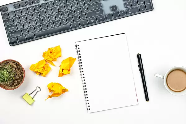 Notepad, pen, crumpled paper balls, cactus plant and pc keyboard on white background