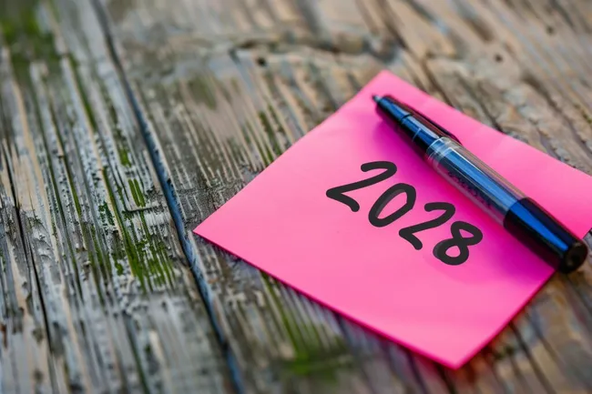 Notizzettel mit Zukunftszahl 2028 und Stift