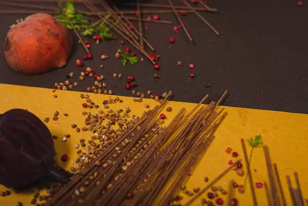 Nudelkomposition mit braunen Spaghetti, Buchweizen, Zwiebel und Granatapfel
