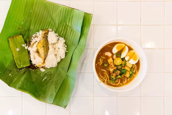 Nudeln mit Garnelen, Eiern und Paprika mit Fisch und Reiß im Palmenblatt