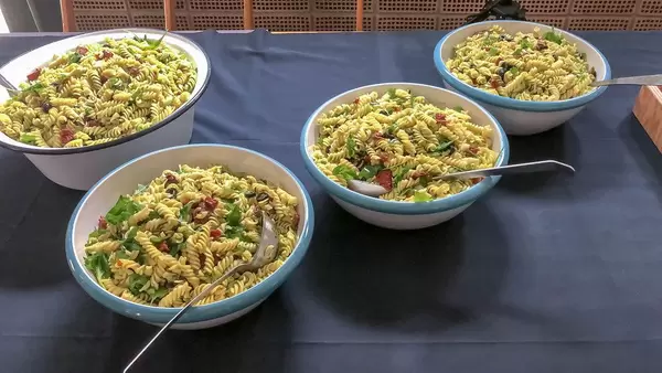 Nudelsalat mit grünen Blättern, in mehreren Schüsseln in Vintageoptik, am Essensbüfett
