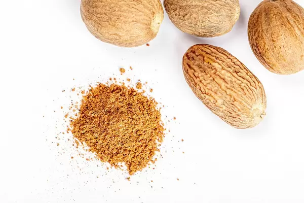 Nutmeg and ground nutmeg on white background, top view