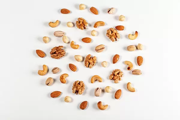 Nuts of different types laid out in the shape of a circle on a white background, top view