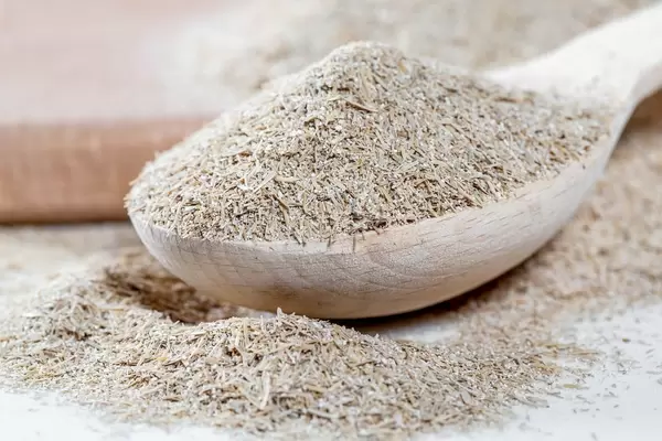 Oat bran in wooden spoon on kitchen board