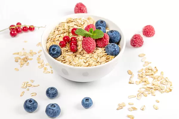 Oat flakes with berries and fresh mint in a bowl and on a white background