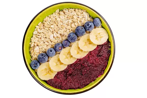 Oat flakes with plum puree, blueberries and banana pieces, top view