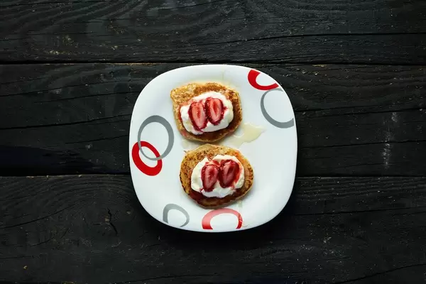 Oat pancakes with fresh yogurt and frozen strawberries and poured honey