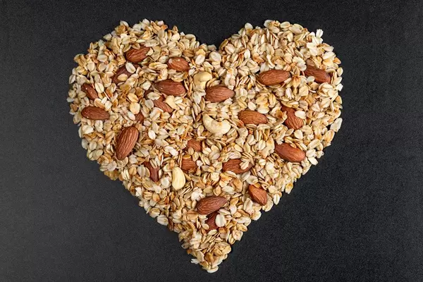 Oatmeal heart with almonds on a black background, top view