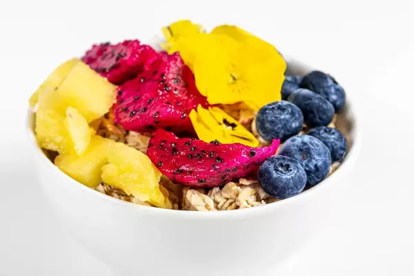 Oatmeal porridge with fresh fruit and yellow flowers