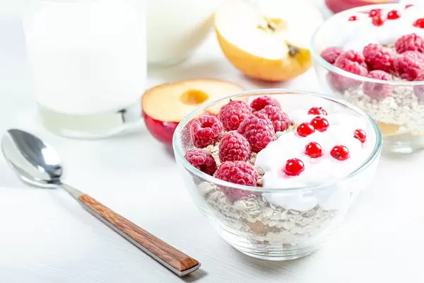 Oatmeal porridge with raspberries and red currant in bowl on white table (Flip 2019)