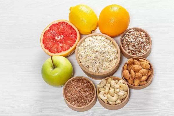 Oatmeal surrounded by nuts and seeds with fresh fruit on a white wooden background. Top view (Flip 2019)