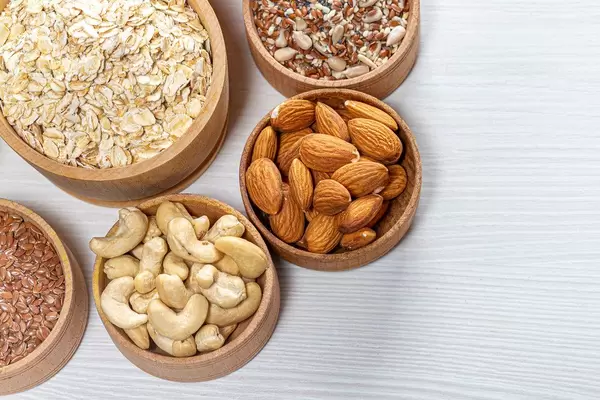 Oatmeal with almonds, cashews, flax seeds and sunflower seeds on a white wooden background. Top view (Flip 2019)
