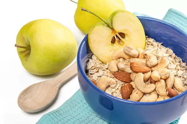 Oatmeal with apple and nuts in a blue bowl, close-up