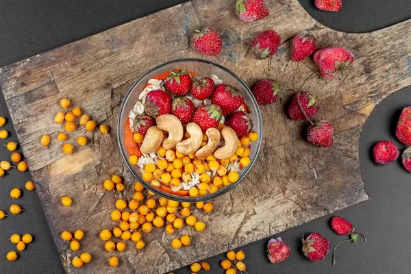 Oatmeal with berries and cashews on dark background, top view (Flip 2020)