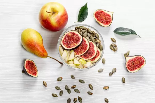 Oatmeal with figs, pears, apples and pumpkin seeds. Top view