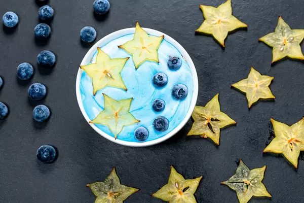 Oatmeal with fresh carambola and blueberry berries on black background. Top view (Flip 2019)