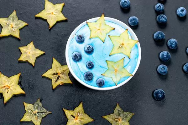 Oatmeal with fresh carambola and blueberry berries on black background. Top view