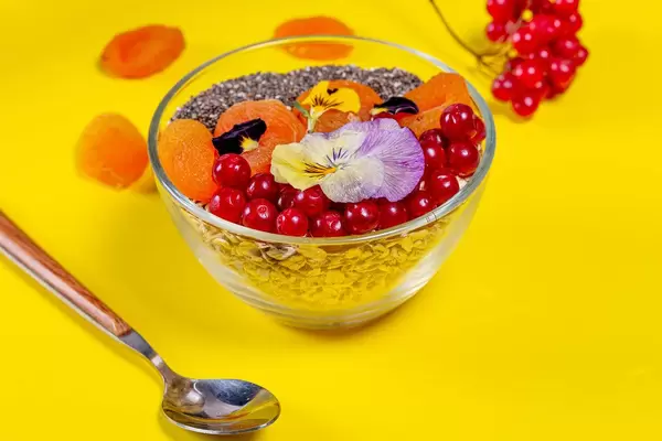Oatmeal with fruit, Chia seeds and flowers on a yellow background (Flip 2019)