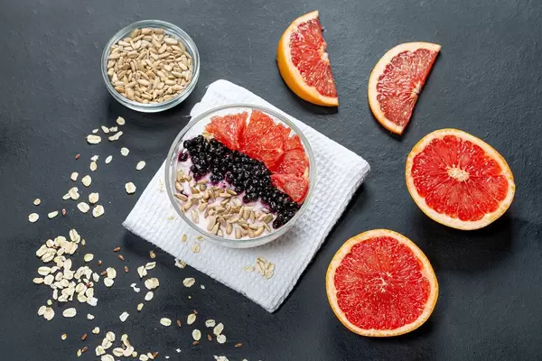 Oatmeal with grapefruit, black elderberry and sunflower seeds on a black background. Top view (Flip 2019)