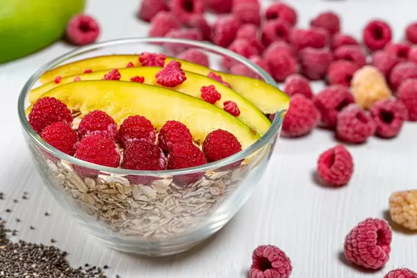 Oatmeal with mango slices, raspberries and Chia seeds in a glass bowl (Flip 2019)
