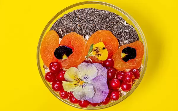 Oatmeal with red berries, dried apricots, Chia seeds and flowers. Top view (Flip 2019)