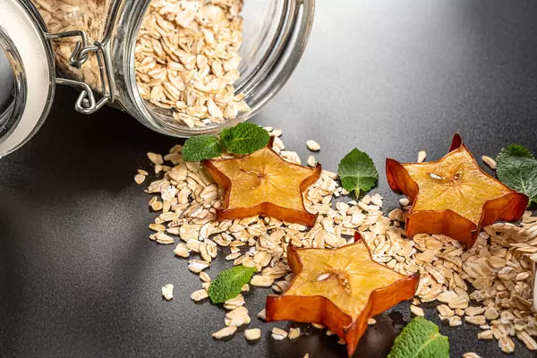 Oatmeal with slices of carom and mint leaves poured from a jar, close-up