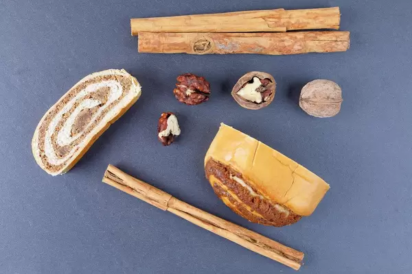 Obene Aufnahme von deutschen Strudel mit Zimtstangen und Walnüssen auf einem grünen Tisch