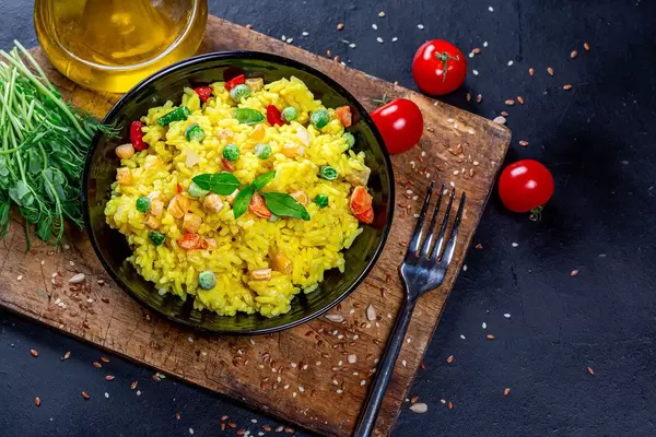 Obene Aufnahme von einem Teller vegetarischen Risotto auf einem rustikalen Holzbrett