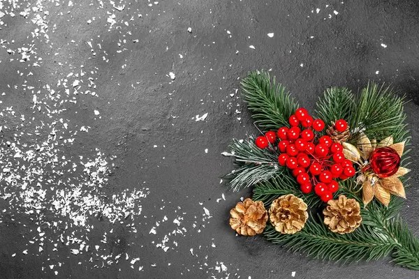 Obene Aufnahme von einer Weihnachtsdekoration aus Zapfen und Tannenzweigen auf schwarzem Tisch