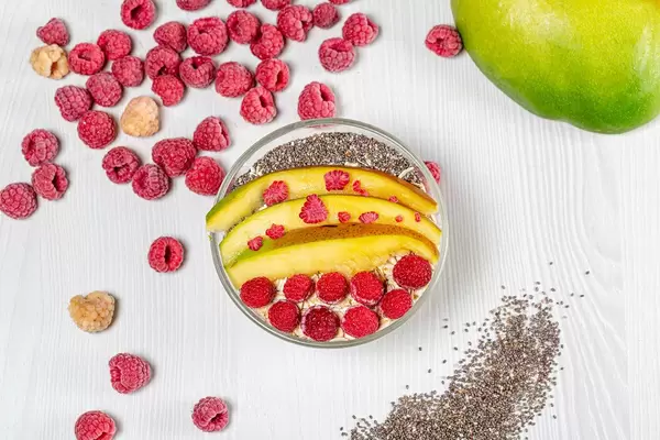 Obene Aufnahme von Haferflocken garniert mit Mango, Himbeeren und Chiasamen
