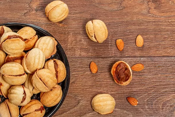 Obene Aufnahme von hausgemachten Walnusskeksen mit Karamellfüllung auf einem Holztisch