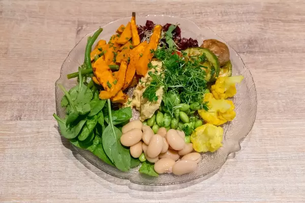 Obene Aufnahme von veganem Salat mit Edamame, Blumenkohl, Spinat, Rote Beete, Zucchini und Pilze