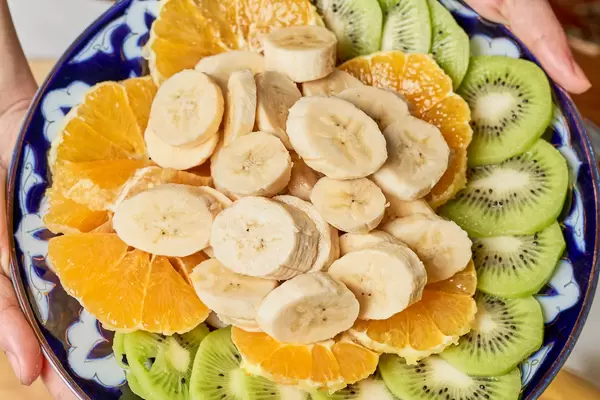 Obstsalat mit Banane, Orange und Kiwi in einer bunten Schüssel: Aufnahme von oben