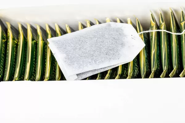 Offener Teebeutel auf verpackten Teebeuteln in einer Packung
