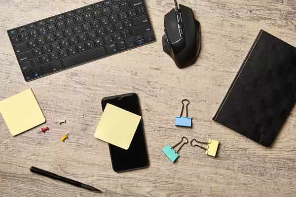 Office workspace with PC keyboard, mouse, notepad and smartphone