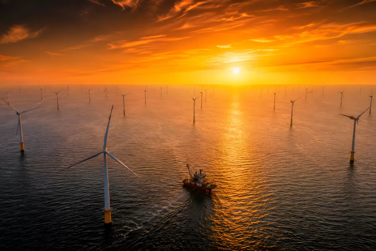 Offshore-Windpark bei Sonnenuntergang mit Versorgungsschiff