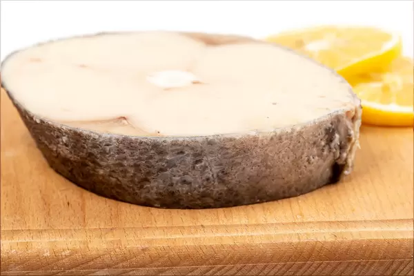 Oily fish steak on wooden board with lemon slices