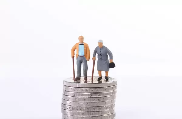 Old couple standing on top of stack of coins