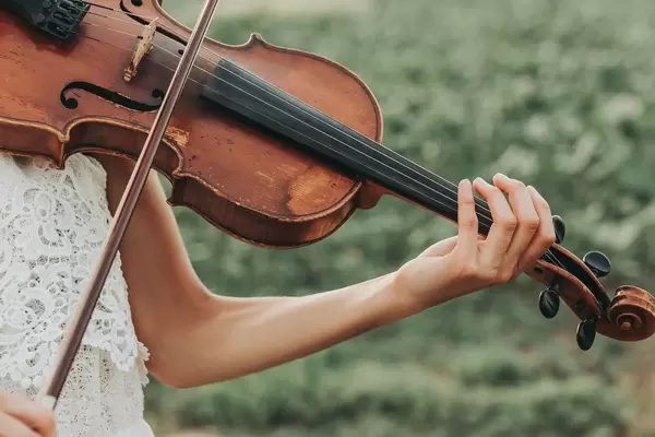 Old violin in the tender female hands of a playing violinist