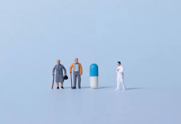 Older couple and doctor with pill on light blue background