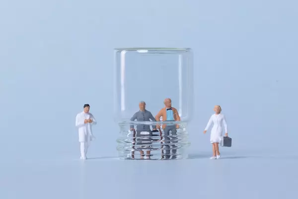 Older couple inside glass and doctors on light blue background