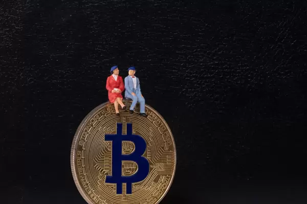 Older couple sitting on a golden Bitcoin