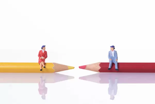 Older couple sitting on red and yellow pencil