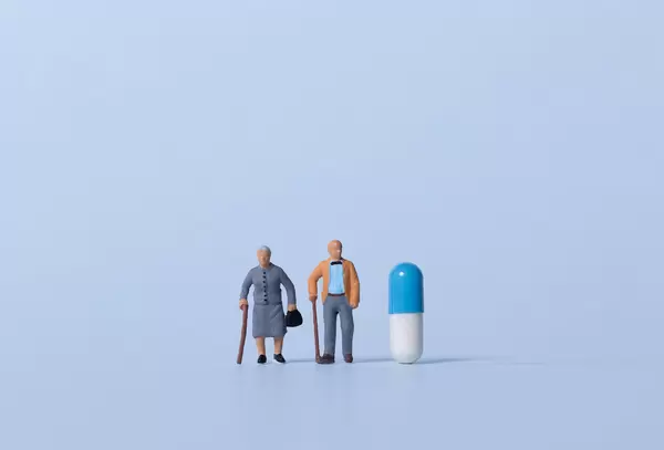 Older couple with pill on light blue background