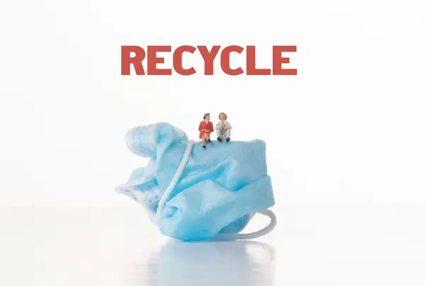 Older man and women sitting on medical face mask with Recycle text