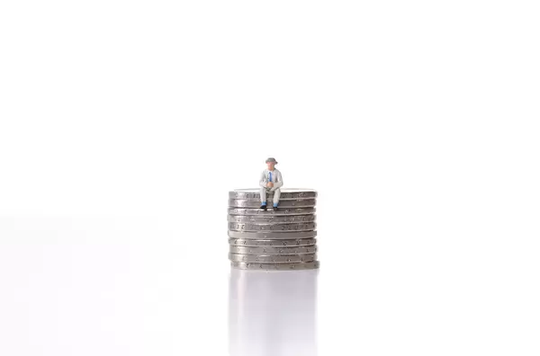Older man sitting on a stack of coins