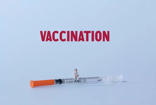Older man sitting on a syringe with Vaccination text