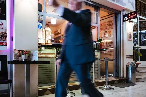 Olderly man walks by a fast-food stand in Athens, Greece