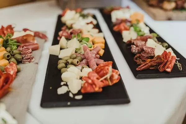 Oliven, Schinken, Käse, Wurst und getrocknete Tomaten auf einem schwarzen Brett auf dekoriertem Tisch